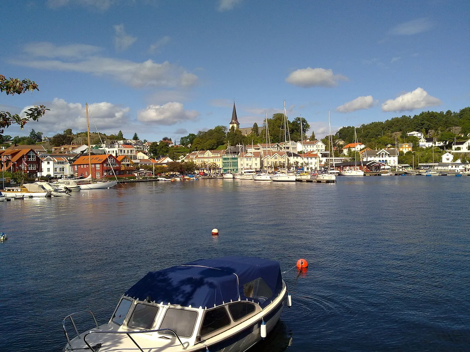 Grimstad sett fra sjøen – hvite trehus og kirkespir bak havnen